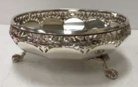 A George V silver bowl with pierced foliate decoration to rim and raised on three claw and ball