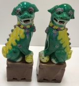 A pair of modern Chinese dogs of Fo ornaments, each dog in green, yellow, blue and pink colouring,