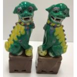 A pair of modern Chinese dogs of Fo ornaments, each dog in green, yellow, blue and pink colouring,