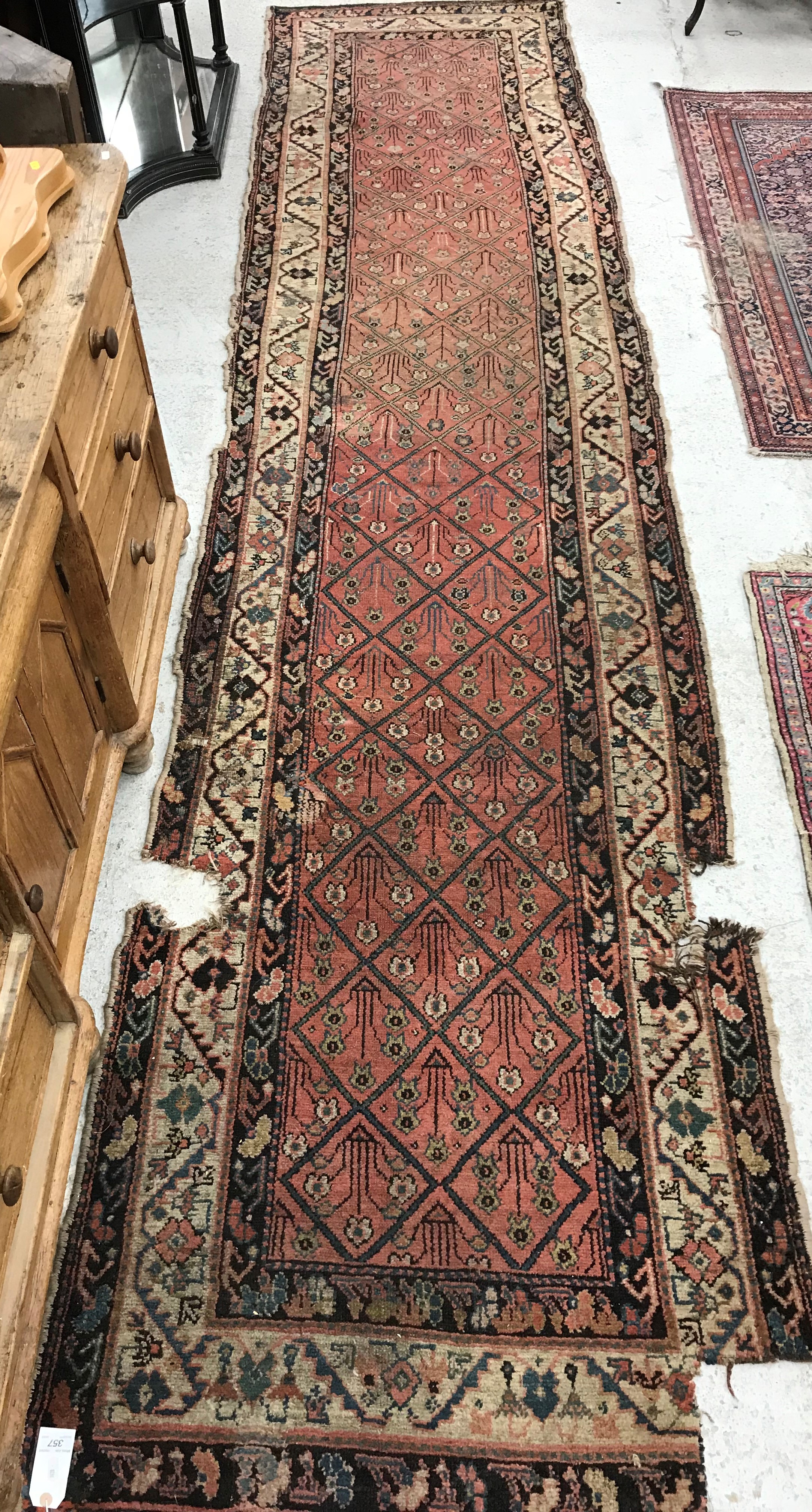 A Persian runner, the central panel set with floral sprays within a grid design, on a pink ground,