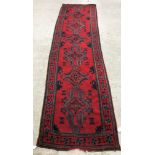 A Donegal style runner, the central panel set with repeating geometric design on a red ground,