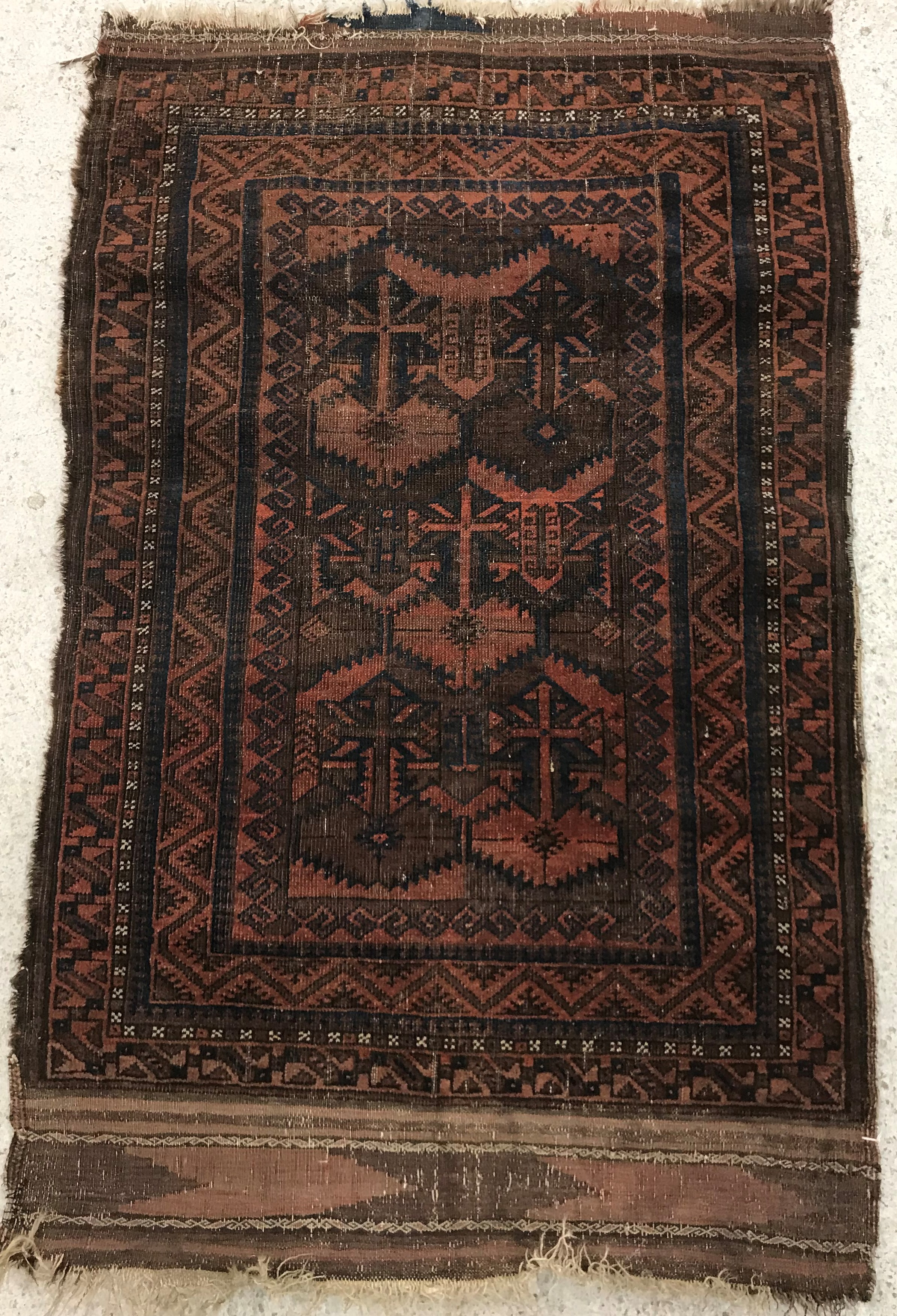 A Belouch rug, the central panel set with geometric design on a red ground,