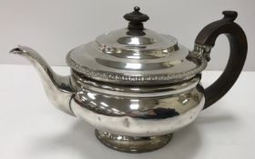 A George IV silver teapot of bellied circular form with ebonised handles and inscribed "A B P