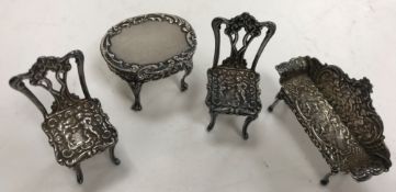 A suite of miniature silver furniture in the Rococo style comprising scroll arm settee,
