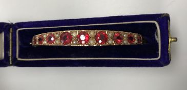 An Edwardian 9 carat gold pearl and red stone set bangle,