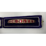 An Edwardian 9 carat gold pearl and red stone set bangle,