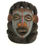 An African carved wooden mask with bead work decoration surrounded by stylised crocodile and mask