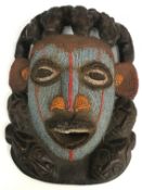 An African carved wooden mask with bead work decoration surrounded by stylised crocodile and mask