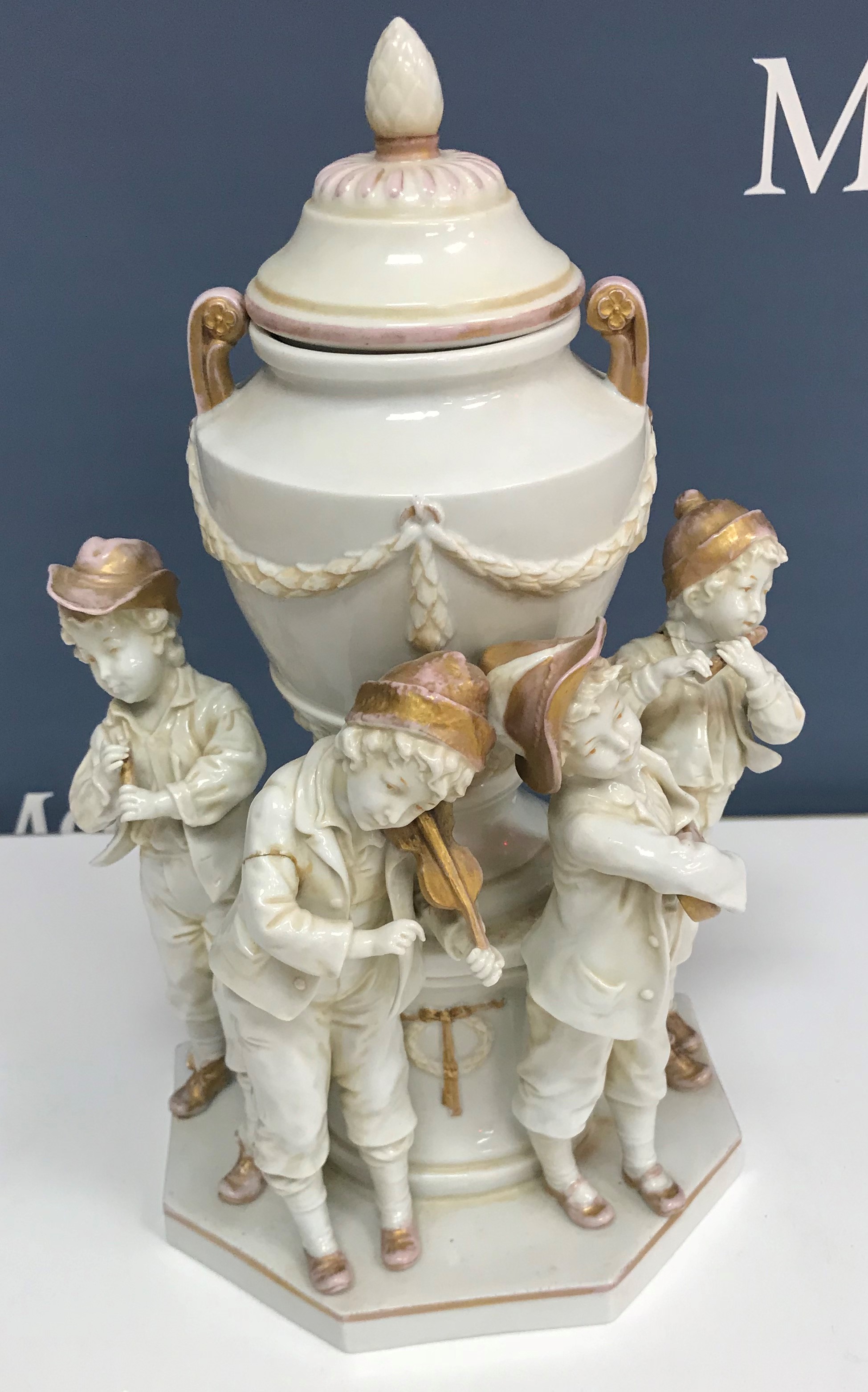 A circa 1900 Capodimonte vase as four young musicians around a large lidded urn with swag