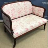 An Edwardian mahogany framed salon settee with carved top rail over an upholstered back and arms