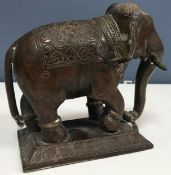 An Indian patinated bronze figure of a ceremonial elephant on rectangular base with lotus leaf