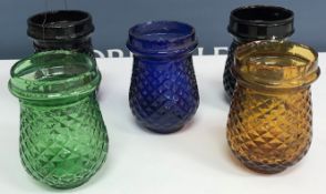 A box containing various glass tea lights of varying colours each approximately 9 cm high