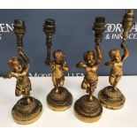 A set of four cast bronze table lamps as cherubs each holding aloft a torch 26 cm high excluding
