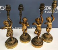 A set of four cast bronze table lamps as cherubs each holding aloft a torch 26 cm high excluding