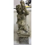 A 20th Century composition stone fountain as a putto with twin fish tails blowing a horn seated