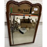 An early 20th Century walnut framed mirror with shaped top and bevelled edged glass 59 cm x 38 cm