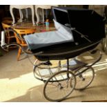 A modern Silver Cross pram with blue canvas covering on a sprung metal base and four spoked wheels