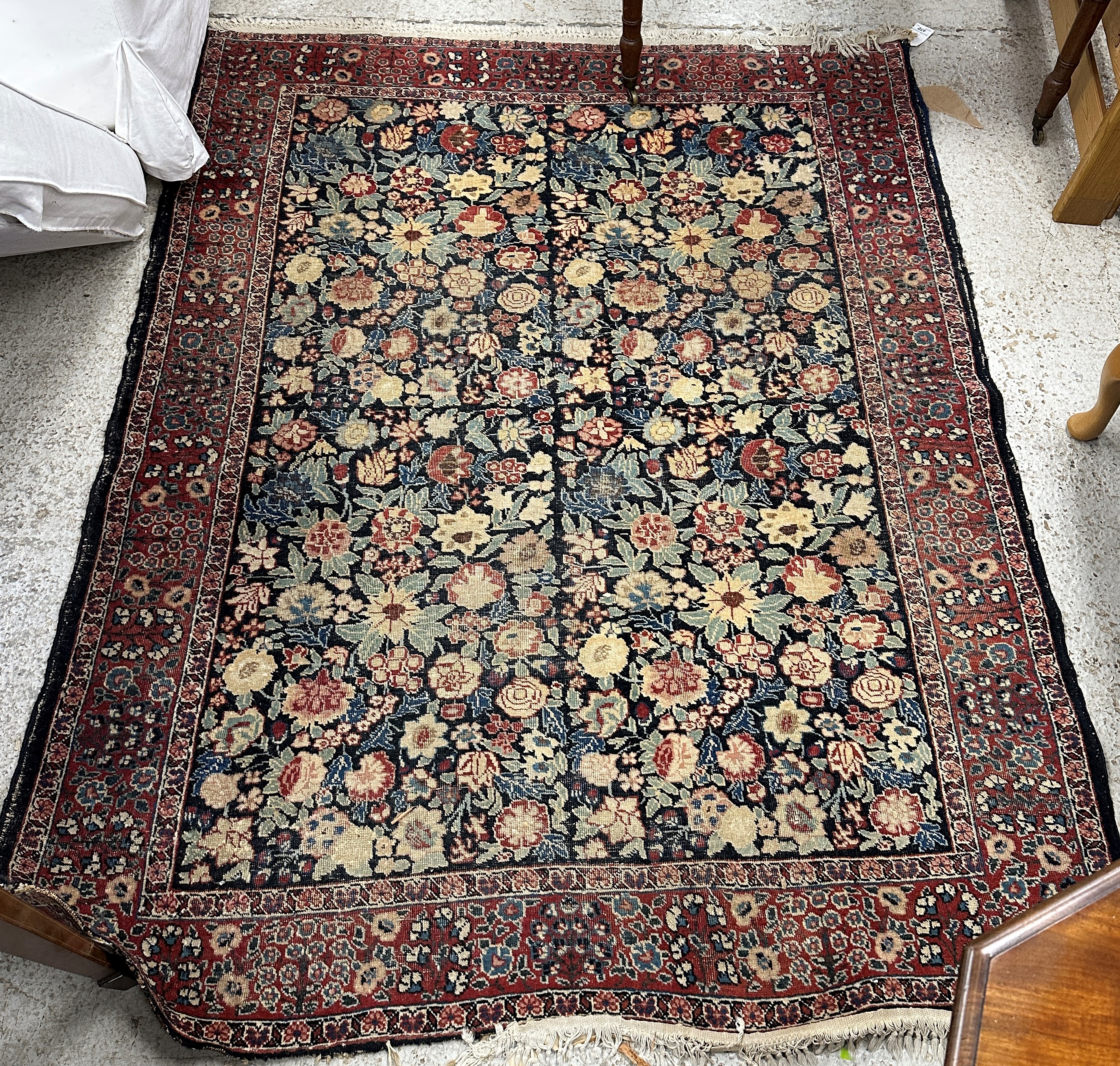 A Persian rug, the central panel set with all-over floral decoration on a dark blue ground,