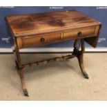 A mahogany and cross banded drop leaf sofa table in the Regency style on lyre end supports to
