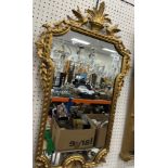 An early 19th Century style gilt and gesso wall mirror with shaped plate with bird and floral