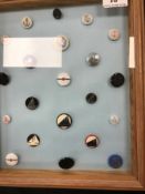 A frame containing a display of nautical themed buttons in bakelite and other materials,