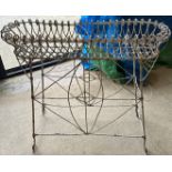 A painted wirework plant stand, the inward scrolling top over lattice work sides,