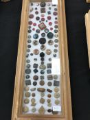 A wooden frame containing a display of mainly wooden buttons,