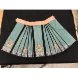 A Chinese teal silk skirt with black borders and a peach waistband, silk panels embroidered in blue,