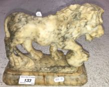 A carved marble figure of a lion with paw on ball on a plinth base 22 cm long x 20 cm high together