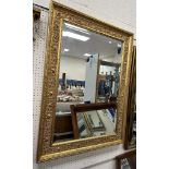 A modern gilt framed wall mirror with scrolling C scrolling and acanthus style decoration with