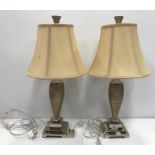 A pair of modern chrome and ribbed table lamps with shades, on stepped bases,