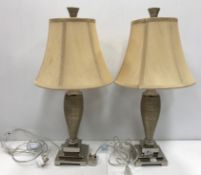 A pair of modern chrome and ribbed table lamps with shades, on stepped bases,