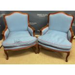 A pair of modern stained beech framed armchairs in the Louis XV style raised on cabriole legs to