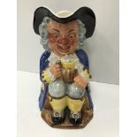 A Clarice Cliff Wilkinsons Ltd Toby jug as "Gentleman in tri-corn and blue long coat seated with an