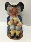 A Clarice Cliff Wilkinsons Ltd Toby jug as "Gentleman in tri-corn and blue long coat seated with an