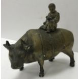 A 19th Century Chinese bronze figure group as a young boy seated on the back of an ox reading a