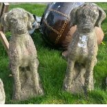 A pair of weathered composition stone figures of seated hounds,