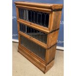 A Globe Wernicke oak three section bookcase with leaded glazed panels on a plinth base 86 cm wide x