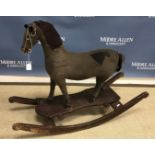 A 19th Century upholstered rocking horse on wooden base with cast iron spoked wheels,