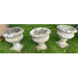 A set of three weathered composition stone urns in the Victorian manner,