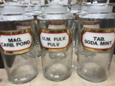 A set of nine cylindrical glass pharmacy jars each with printed labels inscribed "Mag.carb.pond.