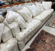 A pair of cream striped upholstered sofas of large proportions, each with five cushions,