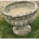 A reconstituted stone planter of circular reeded form, raised on a circular foot,
