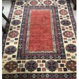 A modern Afghan woollen rug, the central panel of plain red within a stepped red,