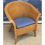 A wicker tub chair and an upholstered tea chest, the upholstery with carp type decoration,