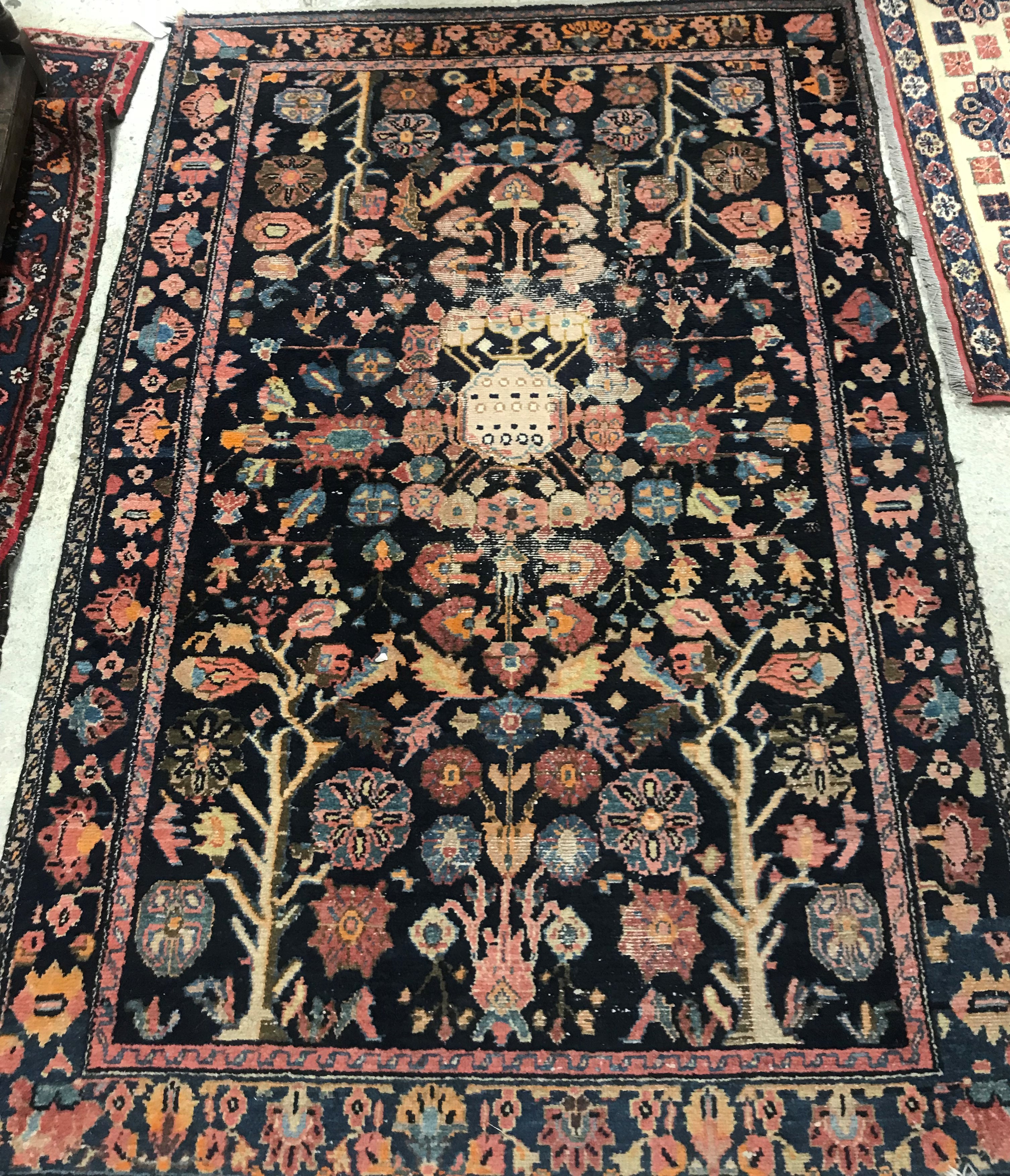 A Persian rug, the central panel set with all-over floral motifs on a dark blue ground,