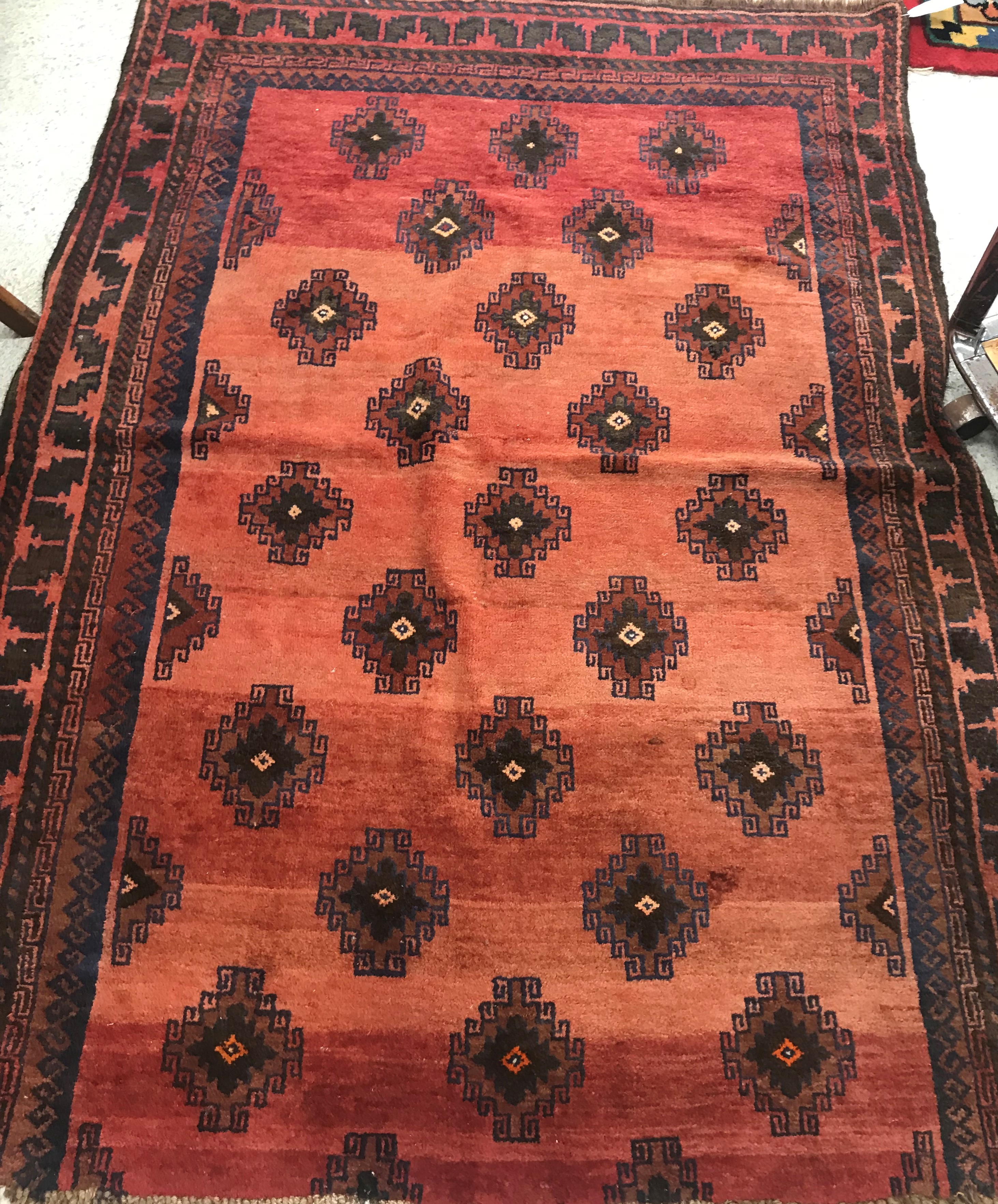 A part Belouch rug, the central panel set with repeating medallions on a red ground,