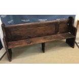 A stained pine chapel pew of plain form on chamfered plank end supports,