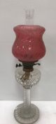 A cut and wrythen glass table lamp with clear glass reservoir and frosted cranberry glass shade 55
