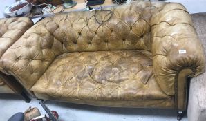 A late Victorian buttoned leather upholstered Chesterfield two seat sofa on turned supports to